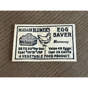 May include: A vintage rectangular label for "Madam Blumer's Egg Saver." The label features illustrations of a basket of eggs and a chicken. Text includes "Blumeroy" and "A Vegetable Food Product."