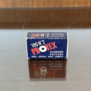 May include: A small rectangular blue box of Protex gummed patches for loose leaf sheets. The box features white and red text that reads 100 N°2 GUMMED PATCHES, 100 N°2 PROTEX GUMMED PATCHES FOR LOOSE LEAF SHEETS, with a white circle in the word PROTEX.