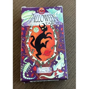 May include: The Halloween Tarot card deck box. The box is purple with illustrations of a black cat, a lizard, a scorpion, and the text "The Halloween Tarot". Created by Kipling West.