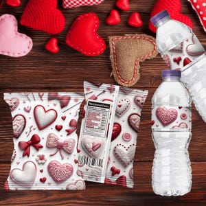 Op de afbeelding: Afbeelding met Valentijnsdagthema met decoratieve harten, strikken en waterflessen. De afbeelding toont een verscheidenheid aan rode, roze en witte harten, sommige gemaakt van stof en andere bedrukt op verpakkingen. Twee waterflessen met hartvormige etiketten zijn ook zichtbaar.
