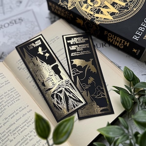 May include: Two black bookmarks with gold foil accents. One bookmark features a castle with the text "I will not die today". The other bookmark features a dragon with the text "A dragon without its rider is a tragedy. A rider without their dragon is dead."
