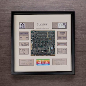 May include: A framed print celebrating the 40th anniversary of the Macintosh computer. The print features a motherboard, a rainbow logo, and the text "Macintosh 1984-2024".