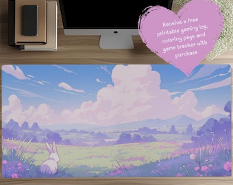 May include: A rectangular desk mat featuring a landscape illustration of a white rabbit in a field of purple and green flowers under a blue sky with large white clouds. A heart-shaped graphic contains the text: Receive a free printable gaming log, coloring page and game tracker with purchase.