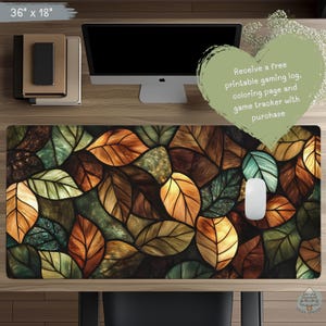 May include: A large 36 inch by 18 inch desk mat featuring a stained glass style pattern of overlapping autumn leaves in shades of orange, brown, green, and yellow. A white computer mouse sits on the mat, which is placed on a wooden desk.