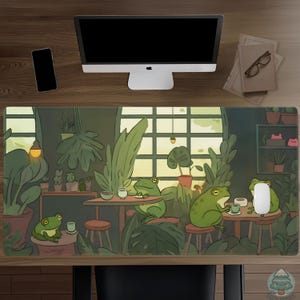 May include: A rectangular desk mat featuring a whimsical illustration of green frogs in a cozy cafe setting. The design includes plants, tables, and cups, with a warm color palette. The mat is designed to protect the desk surface.