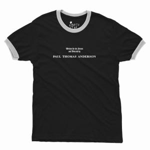 Peut inclure: T-shirt noir à col rond et manches blanches. Le texte "Written for the Screen and Directed by PAUL THOMAS ANDERSON" est imprimé en blanc. Un petit logo est visible en haut. Vêtement décontracté.