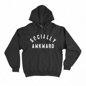May include: Black hoodie with the white text "SOCIALLY AWKWARD" arched across the chest. It features a front pocket and a drawstring hood. The sweatshirt is made from a soft, comfortable fabric, suitable for casual wear.