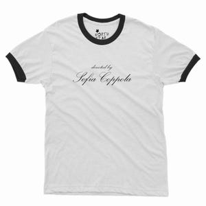 May include: White ringer t-shirt with black trim on the collar and sleeves. The shirt features the text "directed by Sofia Coppola" in a cursive font. The North Star logo is at the top.