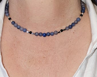 May include: A delicate necklace with blue and gray beads and silver accents. The necklace is made of natural stones and is perfect for everyday wear.