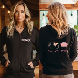 May include: Black zip-up hoodie with the word "NURSE" on the front and "Peace Love Nursing" with a peace sign, heart with a stethoscope, and a nurse's cap on the back.
