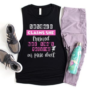 May include: Black muscle tank top with the text "Suspect Claims She Trained But She's Relying on Pixie Dust." Also pictured are gray sneakers, lavender leggings, and a teal water bottle.