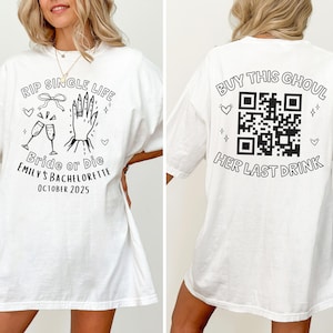 May include: White t-shirt with black text and graphics. The front reads "RIP SINGLE LIFE Bride or Die EMILY'S BACHELORETTE OCTOBER 2025" with illustrations. The back says "BUY THIS GHOUL HER LAST DRINK" with a QR code.