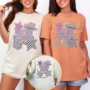 May include: Two t-shirts, one cream and one orange, with graphic designs. The cream shirt says "GETTIN HITCHED" with a cowboy hat and star. The orange shirt says "GETTIN ROWDY" with a heart made of hands and a star. The back of the cream shirt says "GETTIN TIPS!"