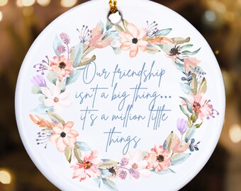 May include: Round white ceramic ornament with a floral wreath design in peach, pink, and lavender hues. The ornament features the text: "Our friendship isn't a big thing... it's a million little things."