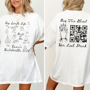 May include: White t-shirt with black graphics and text. The front features the phrase "Rip Single Life" with various illustrations and "Emma's Bachelorette 2025." The back says "Buy This Ghoul" and "Her Last Drink."
