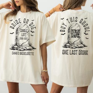 May include: Cream-colored t-shirt with a tombstone graphic. The front reads "Bride or Die" and "Single Life 2000-2025" with "Emma's Bachelorette" below. The back says "Buy This Ghoul" and "One Last Drink".