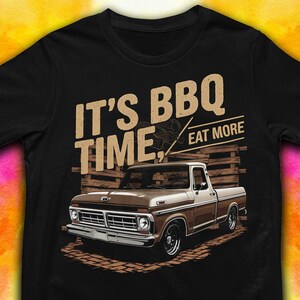 May include: A black t-shirt with a vintage-style illustration of a brown pickup truck and the text "It's BBQ Time, Eat More".