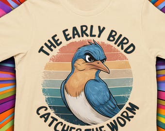 May include: A beige t-shirt with a vintage-style graphic of a bluebird with a grumpy expression. The graphic is surrounded by a circle with the text "The Early Bird Catches The Worm".