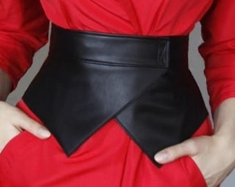 May include: A black leather belt with a pointed, asymmetrical design. The belt is worn over a red shirt.