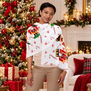 May include: A white scarf featuring a repeating pattern of colorful nutcracker figures, red and white striped candy canes, and round peppermint candies. The lightweight fabric has a soft, fringed edge detail along the bottom hem.