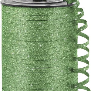 May include: A spool of green glitter ribbon with a black plastic base. The ribbon is a light green color and has a sparkly, glittery texture. Some of the ribbon is curled, showing its flexibility. Ideal for gift wrapping and crafts.