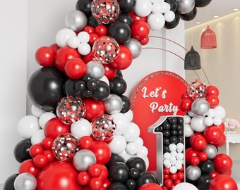 May include: A red, white, and black balloon arch with the words "Let's Party" on a red background. The arch is decorated with confetti balloons and a large number one balloon.
