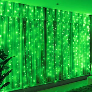 May include: A set of floor-length curtains illuminated by numerous small, bright green LED string lights. The lights are arranged in vertical strands, creating a glowing effect across the fabric surface of the pleated window drapery.