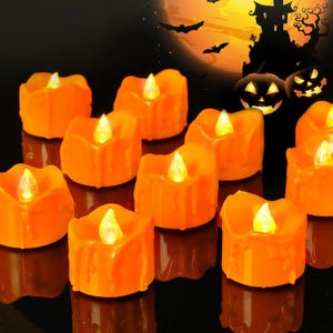 May include: A collection of orange LED tea light candles with a melted wax drip design. Each candle features a small, glowing yellow flame-shaped bulb at the center. The candles are arranged in a group, emitting a warm light against a dark background.