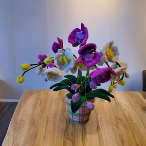 Peut inclure: Une composition florale d'orchidées en crochet dans un pot à motifs rose et blanc. Les fleurs sont roses, blanches et jaunes.