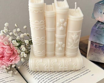 May include: A set of three white candle books with decorative details. The candles are stacked on top of each other and have a vintage book look.