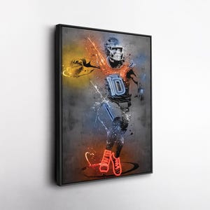 May include: A framed artwork depicts a football player in action, rendered in a neon-style design. The player is wearing a helmet and uniform with the number 10. The artwork features vibrant orange, blue, and yellow accents against a gray background.
