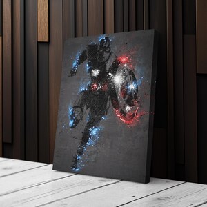 K&ouml;nnte beinhalten: Leinwanddruck mit einer stilisierten Illustration von Captain America in einer Laufpose. Das Kunstwerk verwendet eine dunkle Farbpalette mit roten und blauen Farbspritzern und einem Schild.