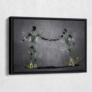 May include: Abstract art print of two basketball players in green and white uniforms, holding hands. The artwork features a gray background with white and green paint splatters, and is framed in black.