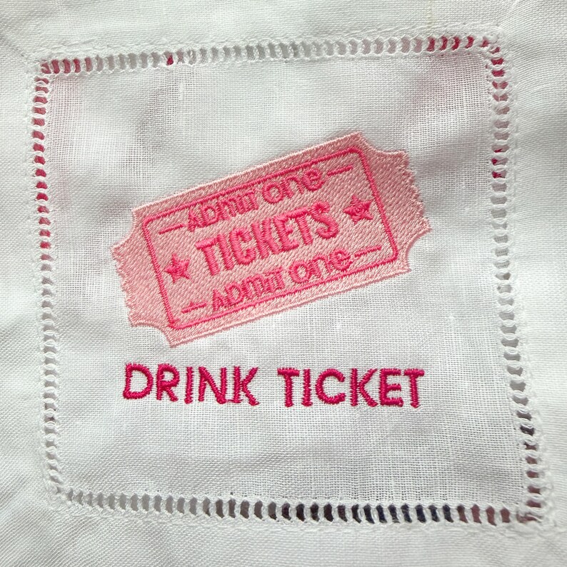 Puede incluir: Servilleta de c&oacute;ctel de lino blanco con un dise&ntilde;o de boleto bordado en rosa. El boleto dice "TICKETS" y "Admit One". Debajo del boleto, las palabras "DRINK TICKET" est&aacute;n bordadas en rosa.