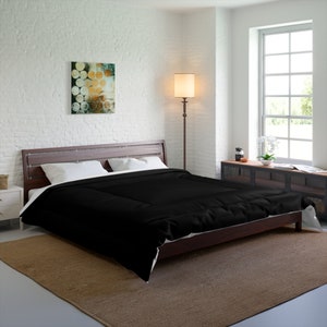 May include: A black comforter on a wooden bed frame with white sheets and pillows. The bed is in a bedroom with a white brick wall, a floor lamp, and a window with white blinds.