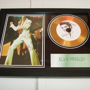 May include: A framed gold disc featuring a photo of Elvis Presley performing on stage. The disc is gold with a picture of Elvis Presley and his signature. The plaque below the disc reads "Elvis Presley".