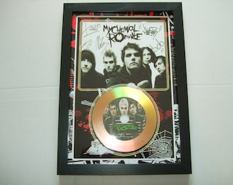 May include: A framed gold record with a black and white photo of the band My Chemical Romance. The record is signed by the band members. The frame has a black background with a red and white spider web design.