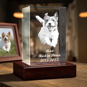 Puede incluir: Un bloque conmemorativo rectangular de cristal transparente con una imagen grabada con láser de un perro saltando. El cristal está montado sobre una base de madera marrón oscuro. El texto "Max", "Rest in Peace" y "2012-2025" está grabado.