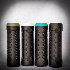 Puede incluir: Cuatro puños de manillar negros con tapas de diferentes colores. Los puños tienen un patrón hexagonal y están hechos de un material similar al caucho. Las tapas son verde, blanca y verde oliva.