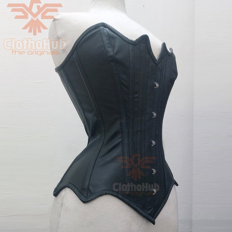 May include: A black leather corset with a sweetheart neckline and a busk closure. The corset has a smooth, shiny finish and is accented with silver-toned metal eyelets and hooks.