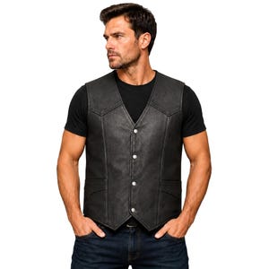 May include: A black leather waistcoat featuring a V-neckline, four silver-toned snap button closures down the centre, and two front pockets with pointed flaps. The garment is worn over a plain black t-shirt and dark blue denim jeans.