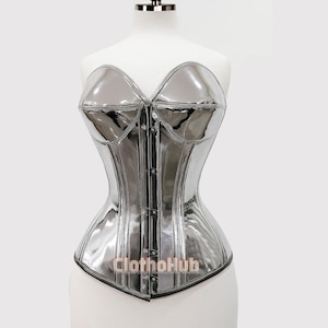 May include: A silver, glossy corset with a sweetheart neckline and a structured silhouette. The corset features a series of buttons down the front and is displayed on a mannequin. The text "Clothohub" is visible at the bottom.