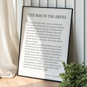 May include: Black and white framed print with a quote by Theodore Roosevelt about the "Man in the Arena". The quote reads: "It is not the critic who counts; not the man who points out how the strong man stumbles, or where the doer of deeds could have done them better. The credit belongs to the man who is actually in the arena, whose face is marred by dust and sweat and blood; who strives valiantly; who errs, who comes short again and again, because there is no effort without error and shortcoming; but who does actually strive to do the deeds; who knows great enthusiasms, the great devotions; who spends himself in a worthy cause; who at the best knows in the end the triumph of high achievement, and who at the worst, if he fails, at least fails while daring greatly, so that his place shall never be with those cold and timid souls who neither know victory nor defeat."