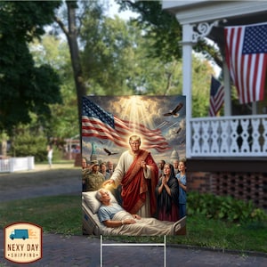 May include: A yard sign featuring a digitally painted image of a man in a hospital bed with a figure in red and white robes, an American flag, and other figures. The sign is displayed outdoors with a house and American flags in the background.