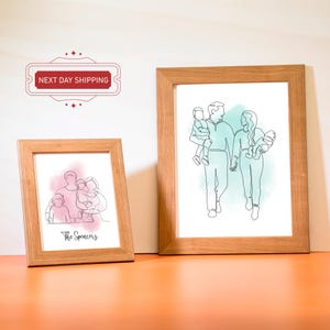 May include: Two framed line drawings of families. The first drawing shows a family of four with a pink watercolor background. The second drawing shows a family of four with a blue watercolor background. Both drawings include the text "The Spencers".