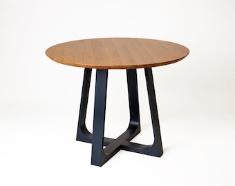 Puede incluir: Una mesa redonda de madera con una tapa marrón oscuro y patas azul marino. Las patas de la mesa tienen un diseño geométrico único, y la mesa está sobre un fondo blanco. La mesa tiene aproximadamente 76 cm de diámetro.