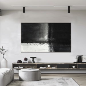 May include: A black and white abstract painting hangs above a wooden shelf with decorative objects. The painting is framed in black and has a textured surface.
