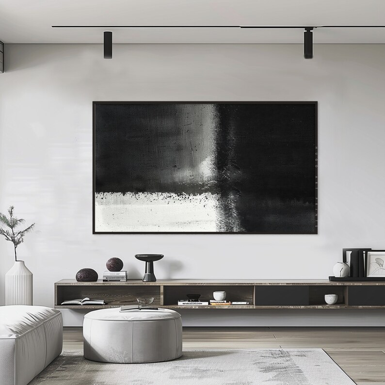 May include: A black and white abstract painting hangs above a wooden shelf with decorative objects. The painting is framed in black and has a textured surface.