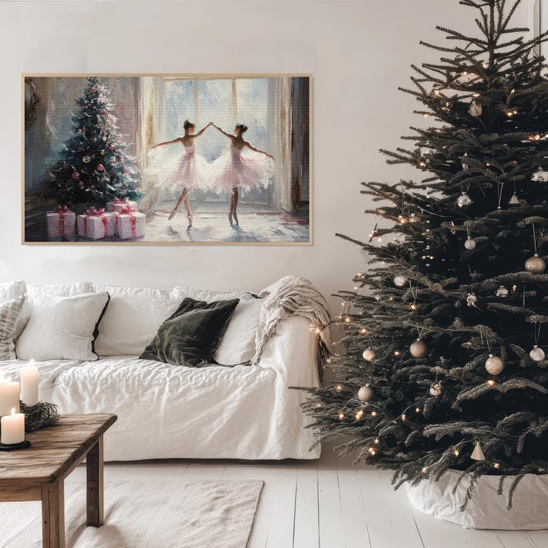 Puede incluir: Una pintura enmarcada de dos bailarinas en tut&uacute;s blancos bailando frente a un &aacute;rbol de Navidad con regalos debajo. La pintura est&aacute; colgada en una pared blanca sobre un sof&aacute; blanco con un coj&iacute;n verde.