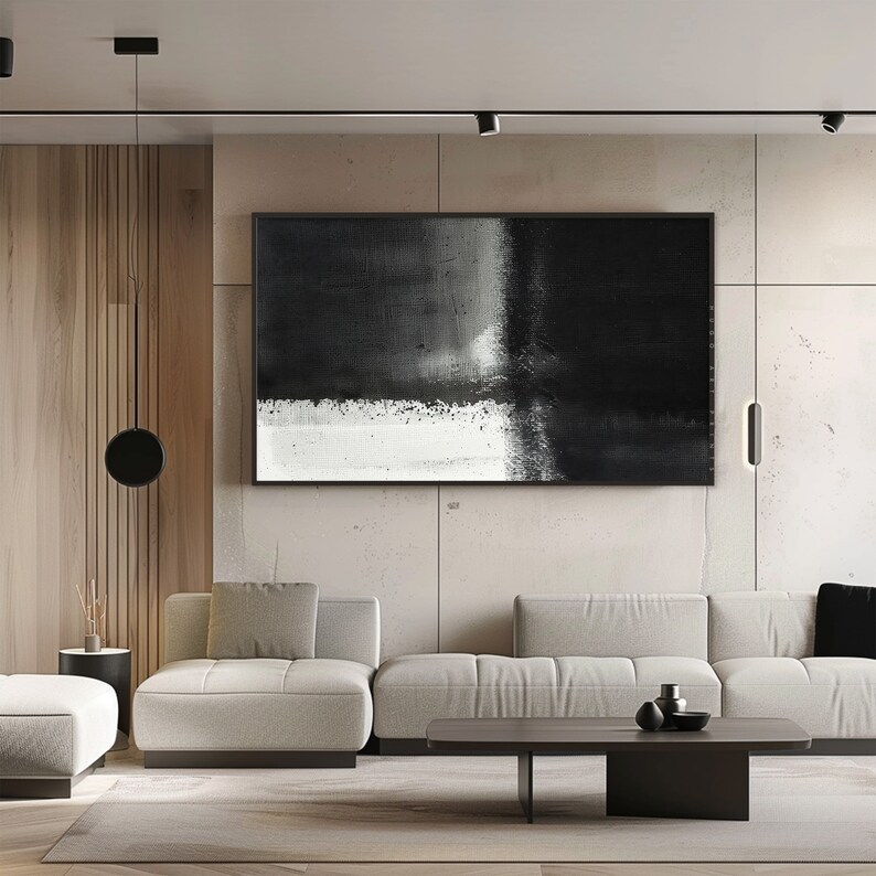 May include: A modern living room interior with a black and white abstract painting hanging on a concrete wall. A gray sectional sofa with pillows sits in front of a dark wood coffee table.